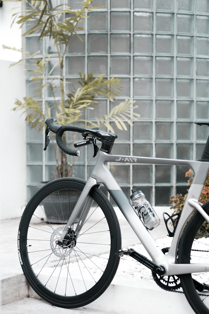 services-04 A sleek silver road bicycle with a water bottle against a glass wall.